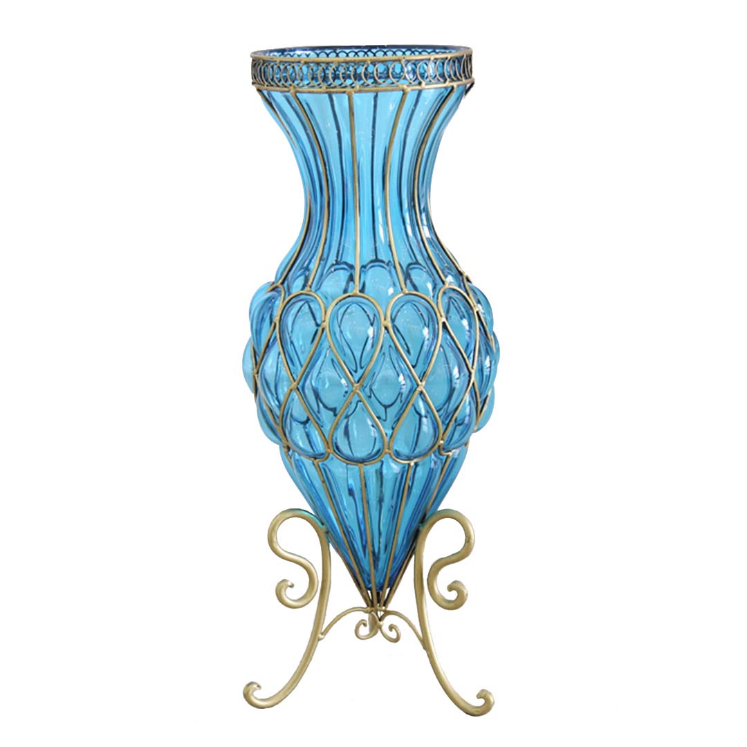 A tall blue glass floor vase with metal flower stand, featuring a geometric pattern on the vase and a gold metal base.